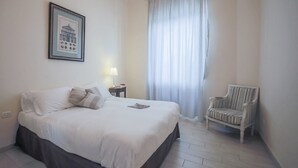 A neatly arranged bedroom with a bed, a chair, a lamp, and a window with curtains. - Ghibellina Loft (Florence)