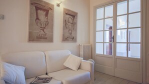 A living room with a white sofa, a magazine on it, and two wall-mounted artworks. - Ghibellina Loft (Florence)
