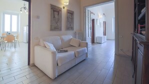 A spacious living room with a white sofa, a dining area with chairs, and a kitchen visible through an open doorway. - Ghibellina Loft (Florence)