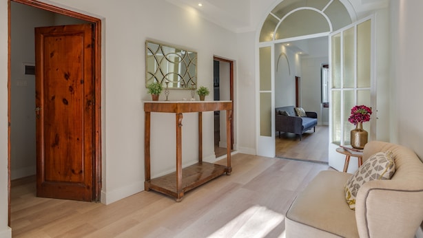 A spacious living area with a wooden door, a console table with potted plants, a sofa with a decorative pillow, and a view into the adjacent room. - Ghibellina Michelangelo (Florence)