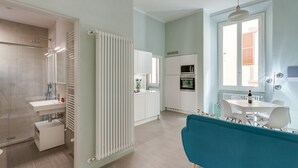 A modern kitchen with white cabinets, a microwave, and a dining area with a table and chairs. - Ginori Terrace (Florence)