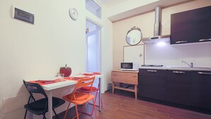 Cozinha compacta com área de refeições, incluindo mesa com cadeiras, micro-ondas e armários.