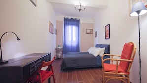 Quarto com cama, escrivaninha, cadeira e abajur.