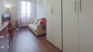 Uma sala de estar moderna com um sofá, uma televisão e uma área de jantar com cadeiras.