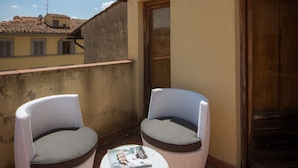 A small outdoor seating area with two wicker chairs and a round table, featuring a magazine and a bottle. - House in Florence Blue (Florence)