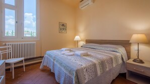 A bedroom with a bed, two bedside lamps, a radiator, a window, and a chair. - House in Florence Blue (Florence)