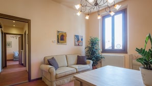 Ein Wohnzimmer mit einem beigefarbenen Sofa, einem Holztisch und einer Topfpflanze.