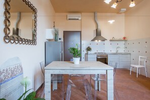 A modern kitchen with a central island, a dining table with chairs, and a white chair in the corner. - House in Florence Red (Florence)