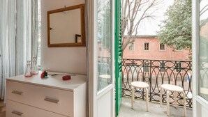 A room with a white dresser, a mirror, and a window with a view of a balcony and buildings. - Liberta Loft (Florence)