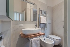 Une salle de bain moderne avec un grand lavabo sur colonne, un bidet et des toilettes.