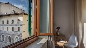 A balcony with a view of historic buildings, a wooden table with a chair, and a vase with flowers. - Luna Chic (Florence)