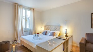 A modern bedroom with a large bed, bedside table, and a view of the city through the window.