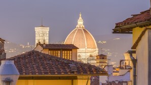 A view of a historic building with a dome and bell tower, surrounded by terracotta-tiled roofs and classic architecture.