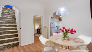 A modern kitchen with white cabinets, a refrigerator, and a dining area with a round table and white chairs.