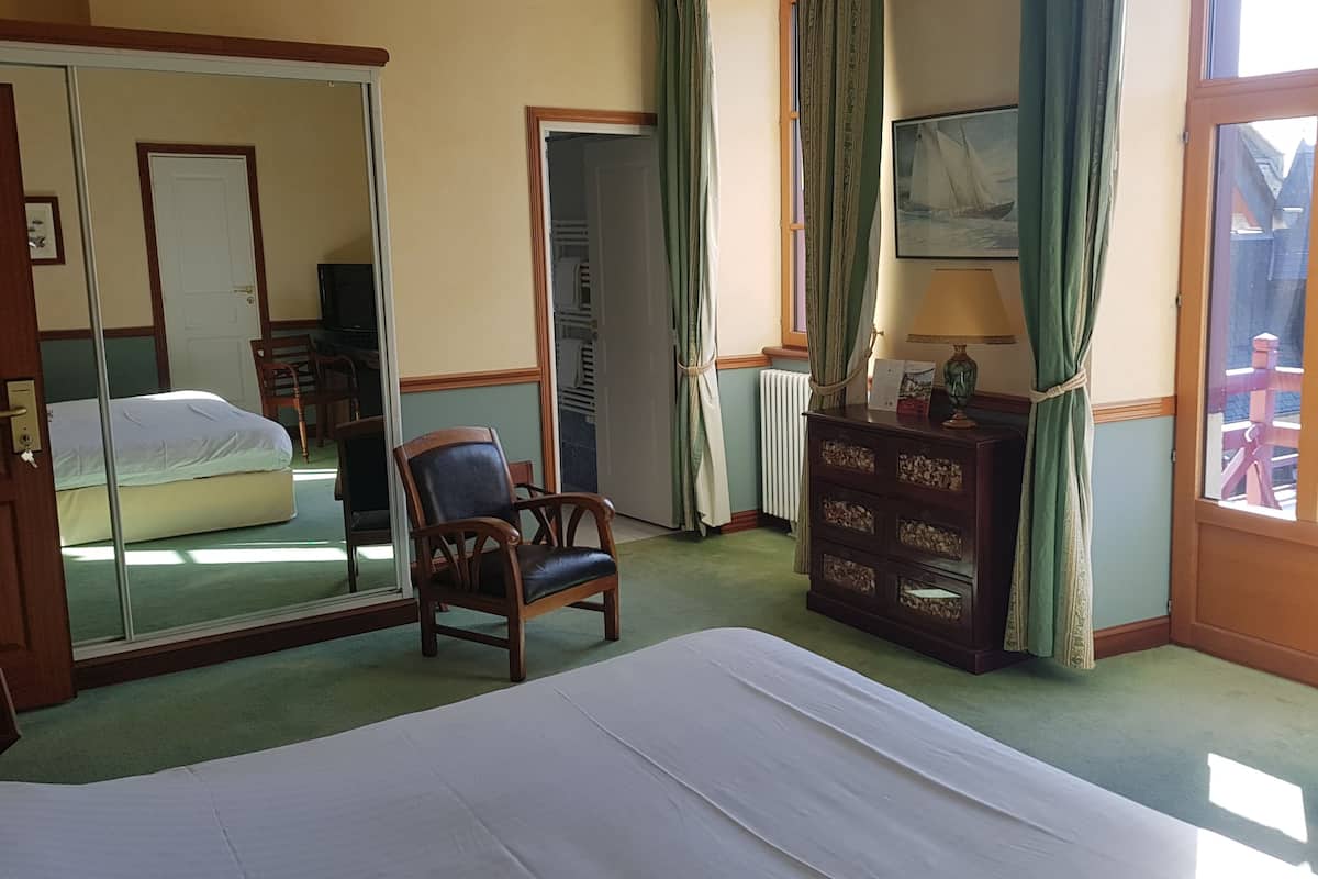 Una habitación de hotel con una cama, una silla, un tocador y un espejo grande.