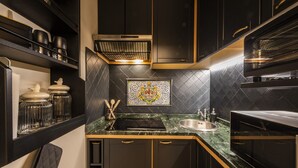 Une cuisine moderne avec des meubles de couleur sombre, un plan de travail noir et un crédence décorative en carreaux.