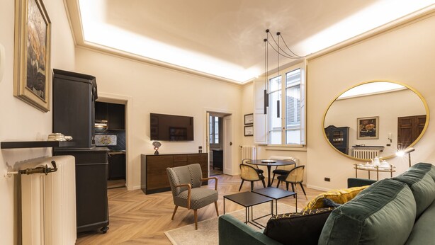 Un salon moderne comprenant un canapé, des fauteuils, une table basse et un coin repas.