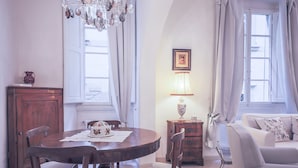 A dining area with a wooden table, chairs, a chandelier, and a white sofa. - Parione (Florence)