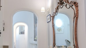 A hallway with a wooden console table and a large ornate mirror. - Parione (Florence)