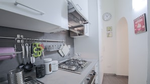 A modern kitchen with stainless steel appliances, a gas stove, and various utensils hanging on the wall. - Parione (Florence)