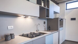 A modern kitchen with a gas stove, a sink, and a built-in oven. There are cabinets above the counter and a window above the sink. - Pepi Loft (Florence)