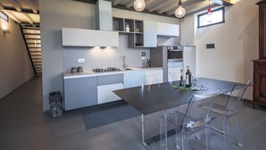 A modern kitchen with a dining area, featuring a dark wooden table, clear chairs, and pendant lighting. - Pepi Loft (Florence)