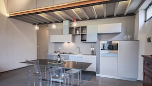 A modern kitchen with a central island, clear chairs, and a dining table. - Pepi Loft (Florence)