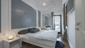 Een moderne slaapkamer met een bed, nachtkastje en een grote spiegel.