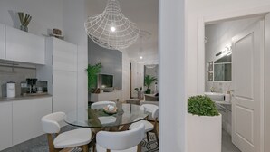 Een moderne keuken met witte kasten, een glazen eettafel en hanglampen.