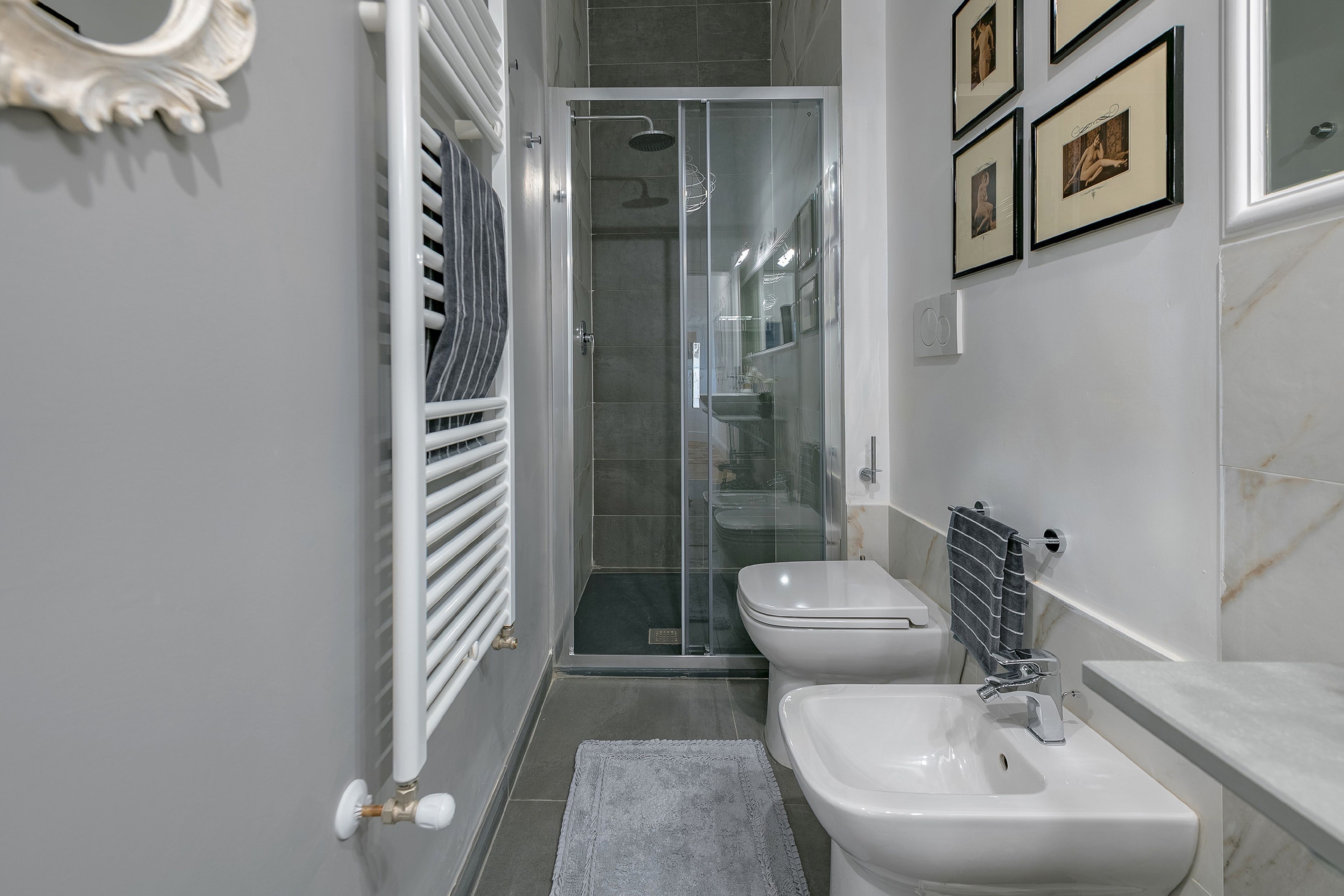 Un baño moderno con cabina de ducha de vidrio, un inodoro blanco, un bidé y un lavamanos.