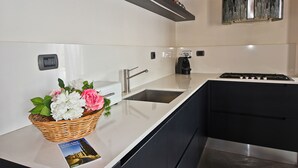 A modern kitchen with a white countertop, stainless steel appliances, and a basket of flowers. - Pergola in Palazzo Leopardi (Florence)