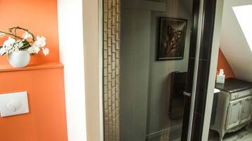 A modern bathroom with a glass shower enclosure, a toilet, and a sink.