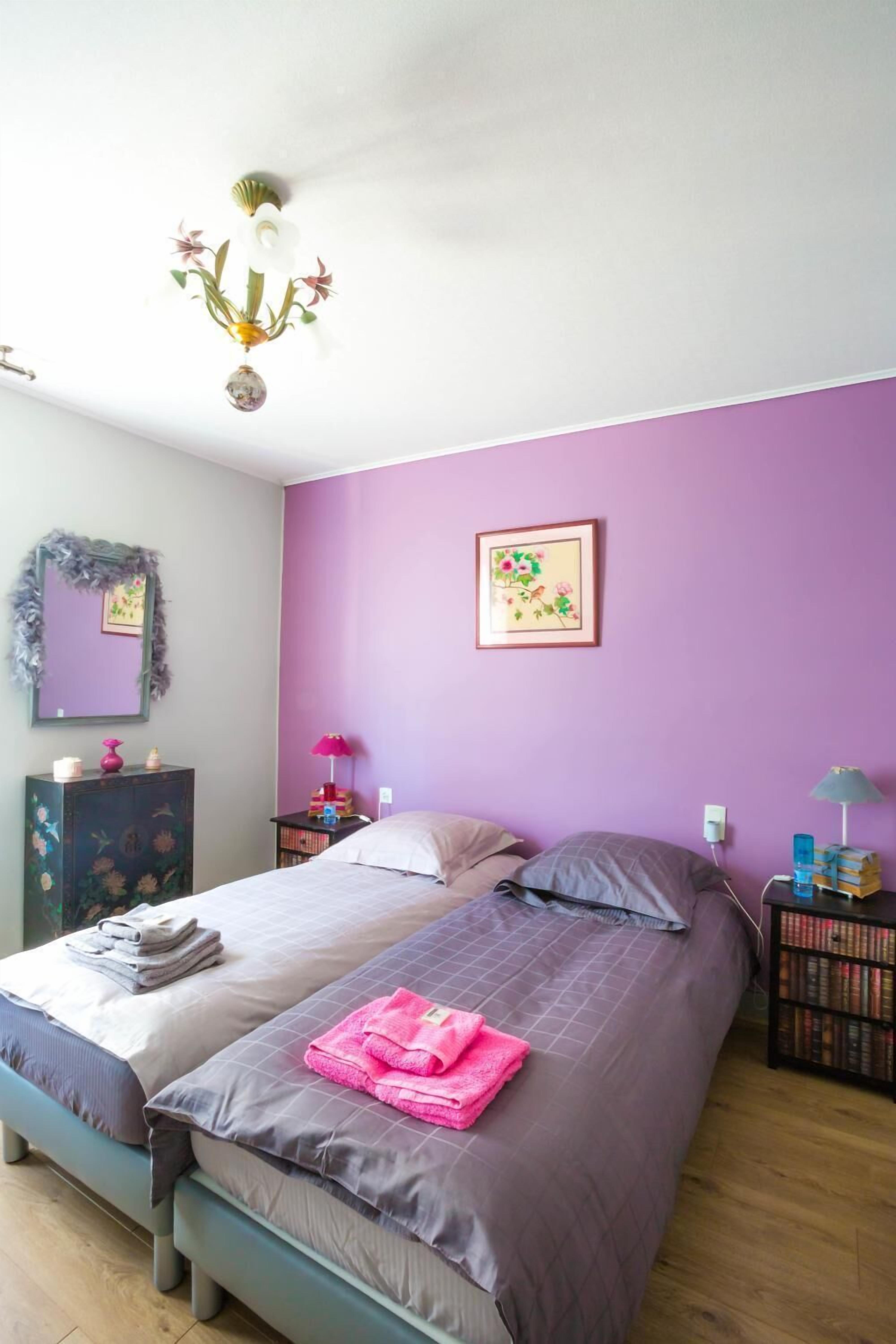 Una camera da letto con due letti, un lampadario, uno specchio, una cassettiera e un quadro appeso al muro.