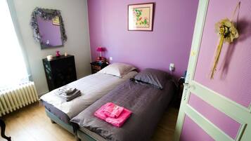 A bedroom with a bed, a dresser, a mirror, a picture on the wall, and a radiator.