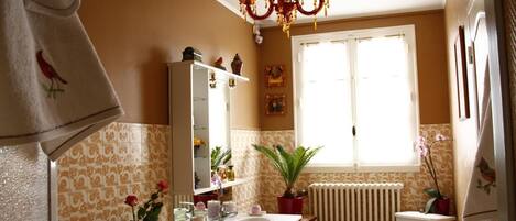 Un baño con lavamanos blanco, espejo, radiador y ventana.