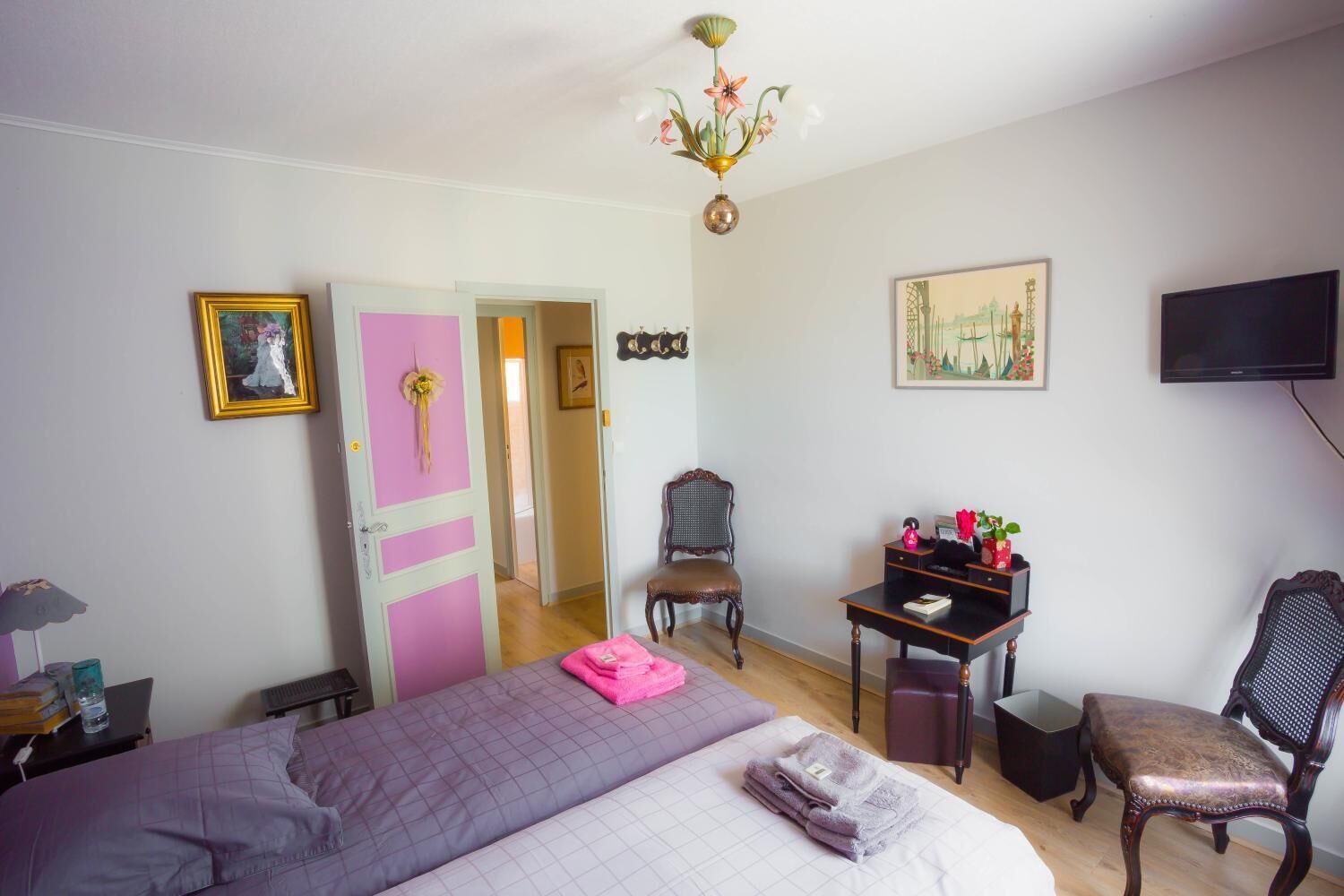 Un dormitorio con cama, escritorio, silla, televisor y puerta.