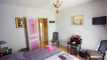 Un dormitorio con cama, escritorio, silla, televisor y puerta.