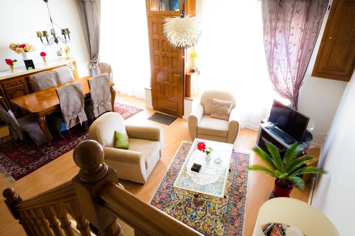 A living room with a dining area, a sofa, a coffee table, a TV, and a potted plant.