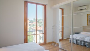 Ein Schlafzimmer mit großem Fenster, einem Kleiderschrank und einem Bett.