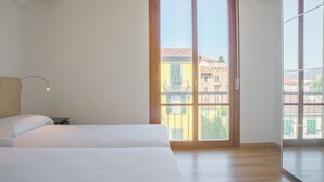 Ein Schlafzimmer mit einem großen Fenster, einem Bett und einem Nachttisch.