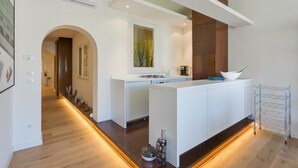 A modern kitchen with a central island, white cabinetry, and a glass rack. - Ponte Vecchio Balcony (Florence)