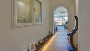 A hallway with a wooden floor, white walls, and a large arched window. - Ponte Vecchio Balcony (Florence)