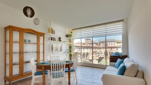 A spacious living room with a dining area, a white sofa, and a large window with a view of buildings. - Ponte Vecchio Balcony (Florence)