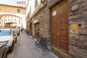 A stone building with a wooden door and a bicycle parked outside. - Ponte Vecchio Balcony (Florence)