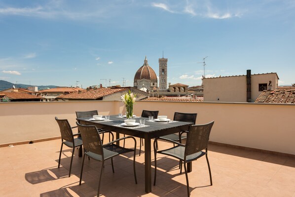 A rooftop terrace with a table set for dining, overlooking a historic building with a dome and bell tower. - Rondinelli Terrace (Florence)