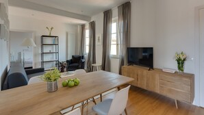 Una sala de estar moderna con una mesa de comedor de madera, un televisor y una estantería.