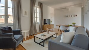 Una sala de estar moderna con un sofá, una mesa de centro y un televisor. Hay un comedor con una mesa y sillas.