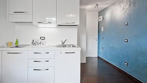 Una cocina moderna con armarios blancos, un lavamanos y una pared de acento azul.