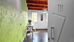 A room with a green wall, a wooden ceiling, a white door, and a window with a view. - San Gallo Suites III (Florence)