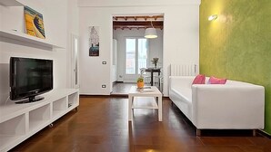A modern living room with a flat-screen TV, white sofa, and a green accent wall. - San Gallo Suites IV (Florence)